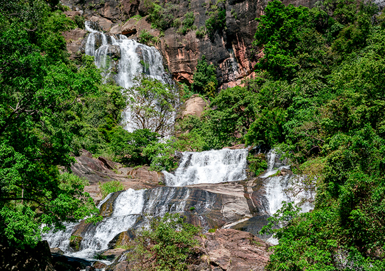 Beautiful Rawana Ella waterfall, surrounded by green tropical forest.